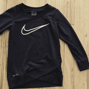 Black Nike long-sleeve shirt with a white swoosh logo on a wooden surface.