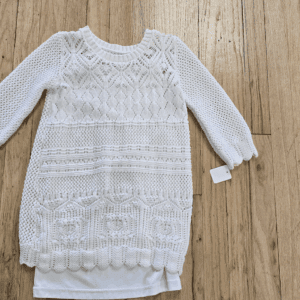 White knitted baby dress with long sleeves and lace accents.