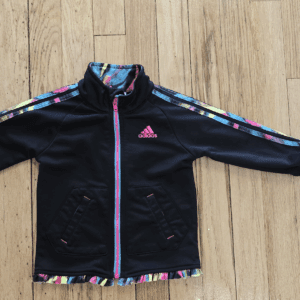 Black Adidas jacket with colorful floral stripes on sleeves and pink zipper.
