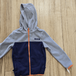 Children's hooded jacket with blue and grey color blocks and orange zipper.