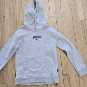 Gray hooded sweatshirt with black text on front, laid flat on wooden floor.