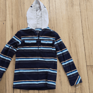 Striped navy blue hoodie with a gray hood laid on wooden floor.