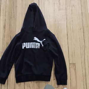Black Puma hoodie with white logo on wooden floor.