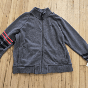 Gray zip-up jacket with red stripes on the sleeve laid flat on a wooden floor.