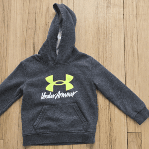 Dark gray Under Armour hoodie with logo on wooden surface.