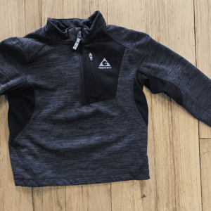 Dark gray quarter-zip pullover with a chest pocket and logo on wooden floor.