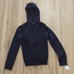 Black zip-up hoodie with pockets laid flat on a wooden floor.