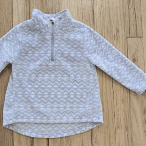 White patterned quarter-zip fleece jacket on wooden floor.