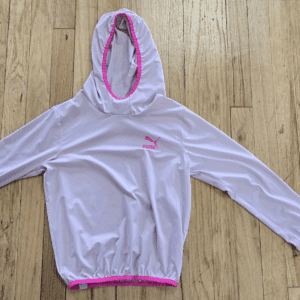 Light purple hooded jacket with pink trim laid out on wooden floor.