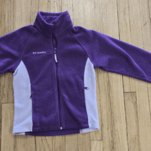 A purple fleece jacket with light purple side panels laid flat on a wooden floor.