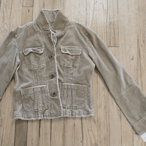 Worn beige denim jacket with frayed hem and front pockets.