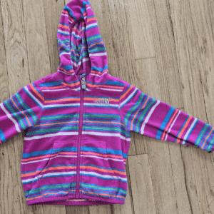 Colorful striped hoodie for a child laid flat on a wooden floor.