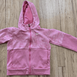Pink hooded jacket with zipper on wooden surface.