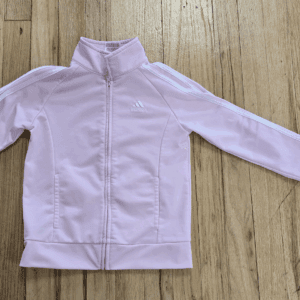 Light pink zip-up jacket laid flat on wooden floor.