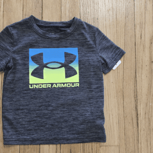 Gray Under Armour t-shirt with a colorful logo on wooden floor.