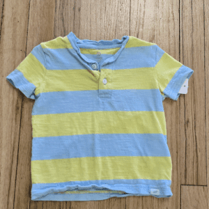 A striped blue and yellow short-sleeve shirt on a wooden surface.