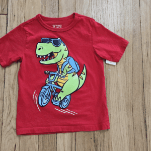Red toddler t-shirt with a dinosaur riding a bicycle graphic.