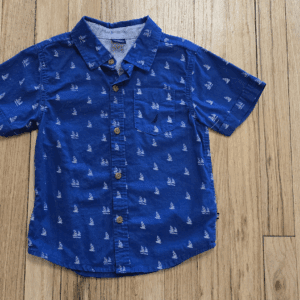 Blue short-sleeve button-up shirt with white patterns on wooden floor.