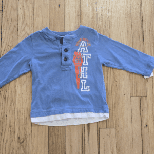 Blue long-sleeve toddler shirt with buttons and layered look.