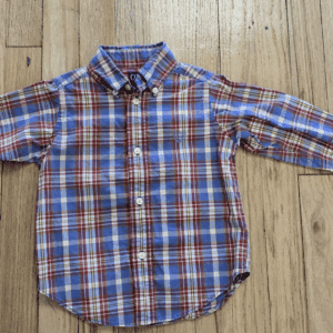 A children's plaid button-up shirt with long sleeves on a wooden floor.