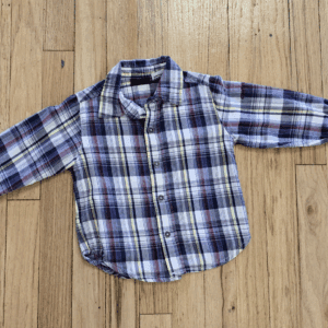 A blue and white plaid long-sleeve shirt for a child on wooden floor.