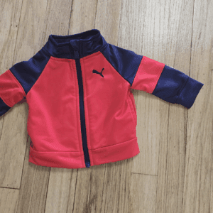 Red and navy blue Puma baby jacket on wooden floor.