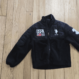 Black USPA jacket with logos on a wooden floor.